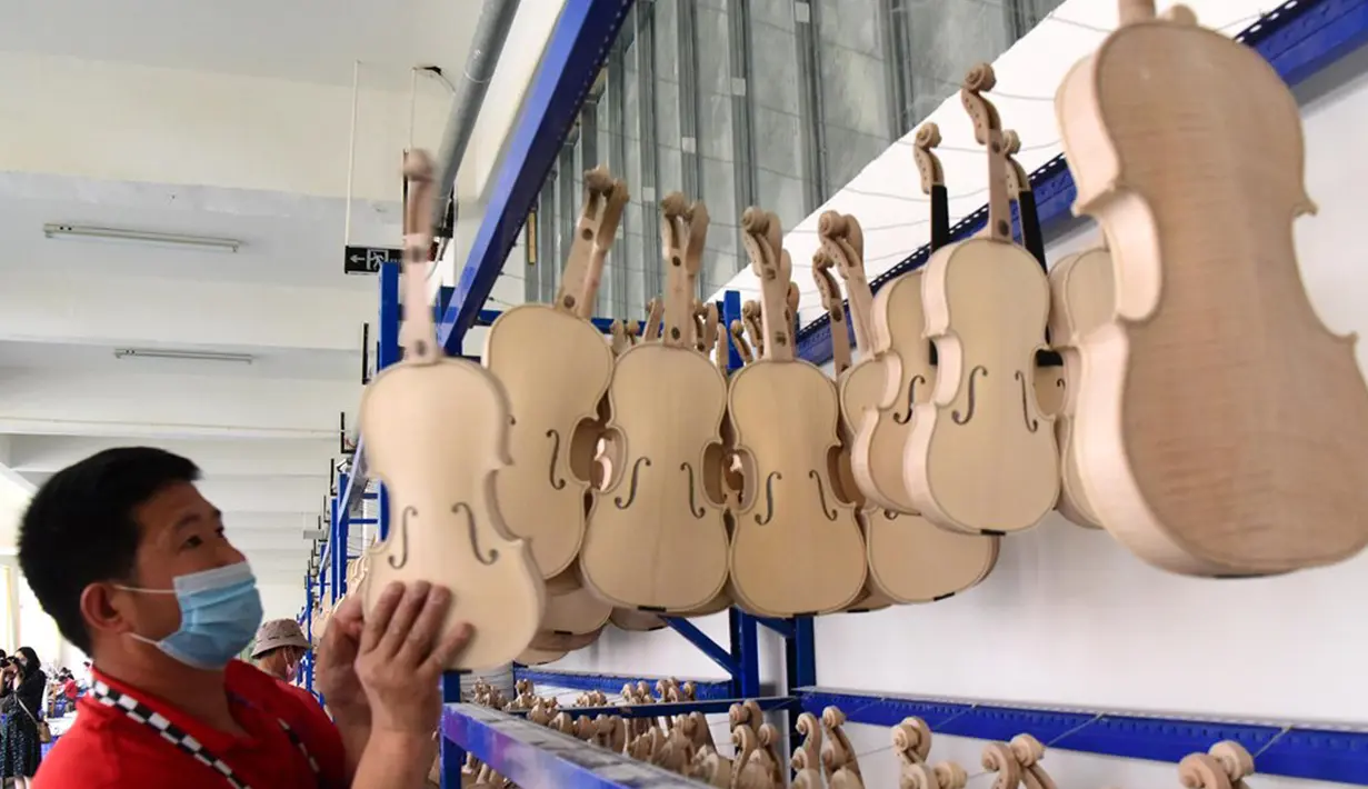 Pekerja menata biola di sebuah bengkel kerja di Queshan, Provinsi Henan, China, Rabu (20/5/2020). Kawasan industri penghasil alat musik tersebut mampu memproduksi 30.000 biola dan selo setiap tahun. (Xinhua/Zhu Xiang)