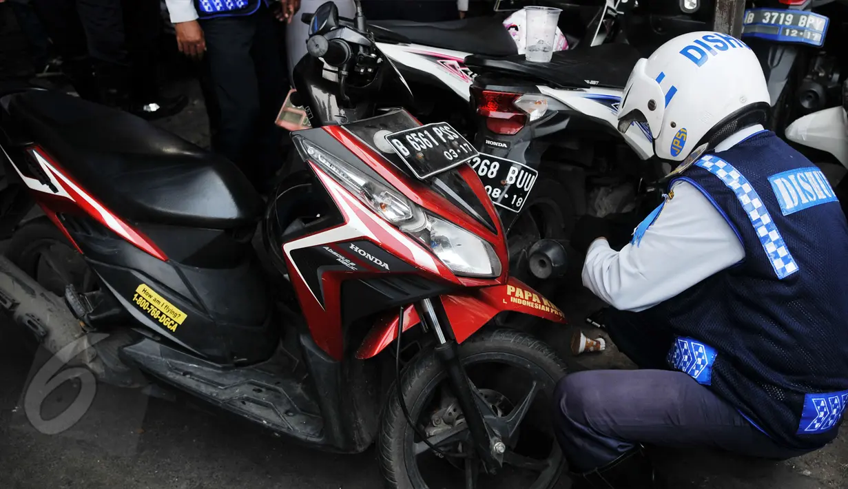  Petugas mencopot pentil motor saat melakukan razia parkir liar di kawasan Tanah Abang, Jakarta, Rabu (3/6/2015). Meski sudah disosialisasikan, kenyataannya masih banyak orang yang tak menghiraukan peraturan tersebut. (Liputan6.com/Johan Tallo)