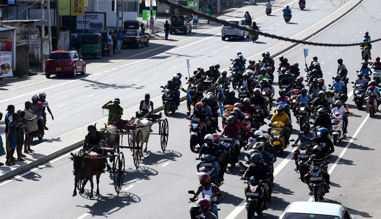 Para pengendara sepeda motor ikut mengikuti dari belakang saat para ppeserta memacu tunggangannya dalam perlombaan balap gerobak sapi di Kolombo, Sri Lanka, Sabtu (20/4). (LAKRUWAN WANNIARACHCHI/AFP)