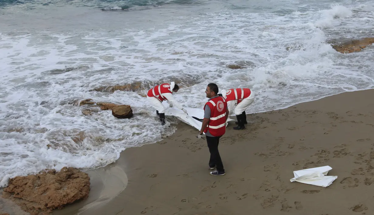 Kelompok Bulan Sabit Merah Libya memasukkan jenazah yang diduga imigran yang tewas tenggelam, ke kantong mayat di pantai Khoms, sebelah timur Tripoli, Minggu (25/10). Sedikitnya 40 jasad telah ditemukan di pantai Libya. (REUTERS/Ismail Zitouny)