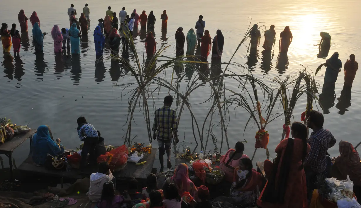 Umat Hindu India berdoa kepada matahari selama Festival Chhath di tepi Danau Hussain Sagar, Hyderabad, Selasa (13/11). Festival Hindu kuno ini dilakukan sebagai bentuk terima kasih kepada Dewa Matahari yang menopang kehidupan di bumi. (NOAH SEELAM / AFP)