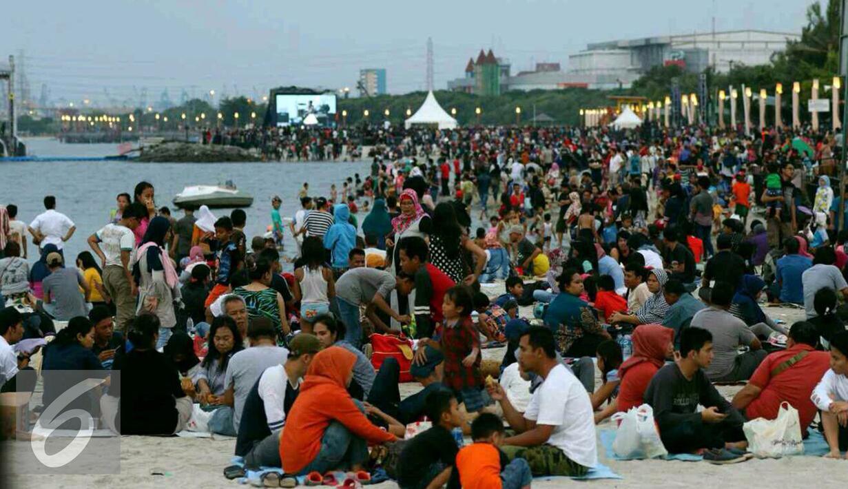 Ribuan pengunjung duduk dipinggir pantai menunggu pergantian tahun baru di Ancol, Jakarta, Sabtu (31/12). Tak hanya duduk-duduk, banyak pula yang bermain pasir dan berenang. (Liputan6.com/Angga Yuniar)