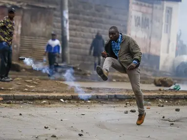 Seorang pria menendang granat gas air mata ke arah polisi selama protes di ibu kota Nairobi, Kenya Jumat (7/7/2023). Lusinan pengunjuk rasa anti-pemerintah ditangkap di Nairobi karena bagian lain negara itu juga menyaksikan demonstrasi yang diserukan oleh oposisi terhadap pajak yang baru dikenakan dan biaya hidup. (AP Photo/Brian Inganga)