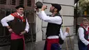Seorang pria yang mengenakan kostum tradisi meminum anggur merah dari Bota, atau kulit anggur yang biasanya terbuat dari kulit binatang sambil menunggu untuk menemani para gembala dan domba-dombanya yang dipandu melalui pusat kota Madrid, Spanyol, Minggu (23/10/2022). (AP Photo/Paul White)