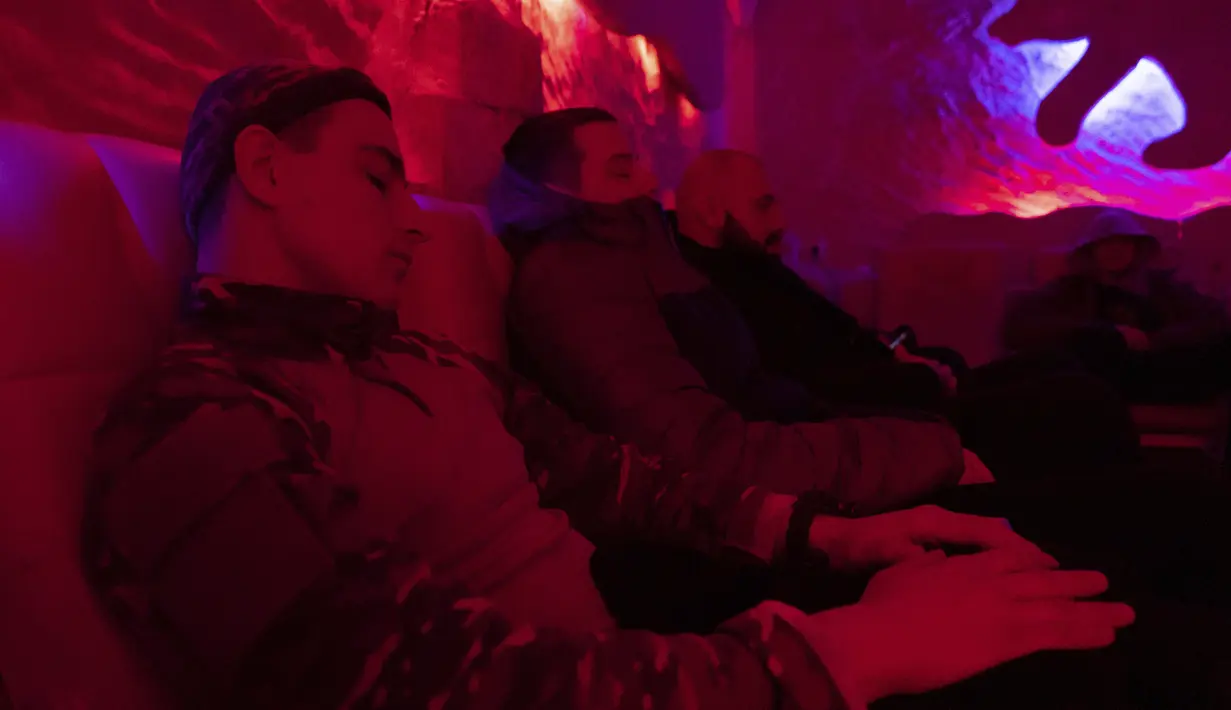 Prajurit Ukraina Viktor 'Shahtar' mendengarkan musik meditasi saat duduk bersama rekan-rekannya di ruangan berpenerangan redup di pusat rehabilitasi wilayah Kharkiv, pada 30 Desember 2022. Viktor, yang bekerja sebagai penambang sebelum bergabung dengan tentara, mengambil bagian dalam operasi militer yang mendorong pasukan pendudukan Rusia keluar dari wilayah Kharkiv. (AP Photo/Vasilisa Stepanenko)