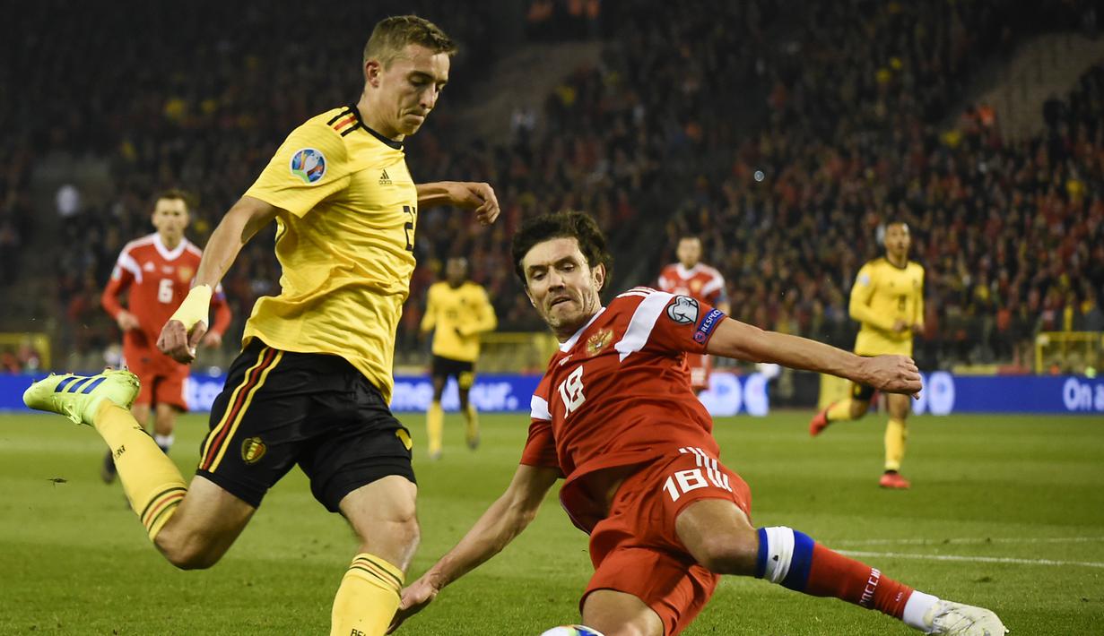 Gelandang Belgia, Timothy Castagne mencoba melewati pemain Rusia, Yuri Zhirkov pada laga perdana Kualifikasi Piala Eropa 2020 Grup I yang berlangsung di Stadion Roi Baudouin, Brussels, Jumat (22/3). Belgia menang 3-1 atas Rusia. (AFP/John Thys)