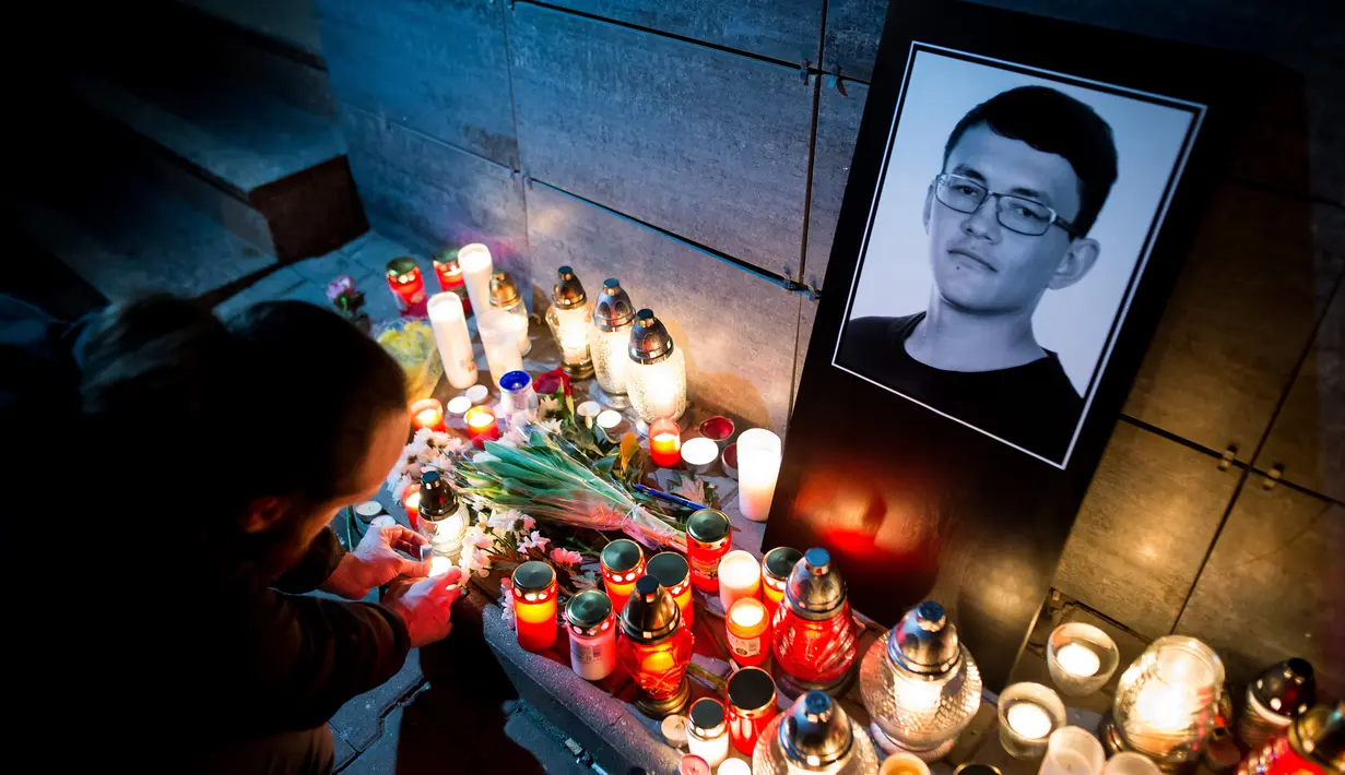 Seorang pria menyalakan lilin di depan foto Jan Kuciak di Bratislava (26/2). Pembunuhan itu terjadi di tengah pembuatan laporan investigatif Kuciak soal kasus dugaan kecurangan pajak yang melibatkan pengusaha. (AFP Photo/Vladimir Simicek)