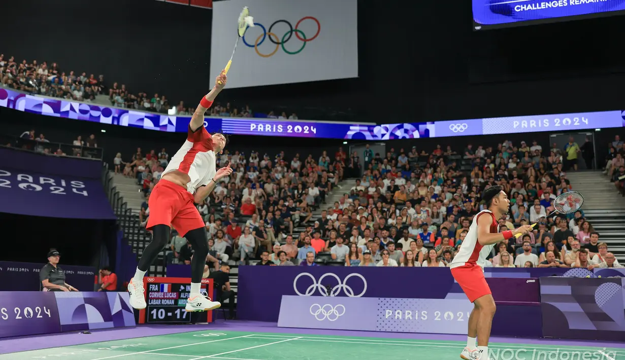 <p>Pemain ganda putra Indonesia, Muhammad Rian Ardianto (belakang) melepaskan drop shot saat menghadapi wakil Prancis, Lucas Corvee/Ronan Labar pada laga Grup C Olimpiade Paris 2024 di Porte De La Chapelle Arena, Paris, Senin (29/7/2024). Fajar Alfian/Muhammad Rian Ardianto menang dua gim langsung 21-13, 21-10. (Dok. NOC Indonesia/Naif Muhammad Al'as)</p>