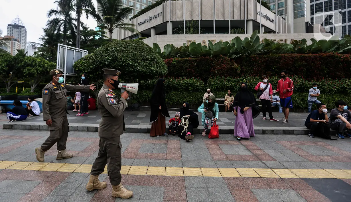 Petugas Satpol PP berkeliling memberikan imbauan di kawasan Bundaran HI, Jakarta, Minggu (6/12/2020). Ikatan Dokter Indonesia (IDI) Jakarta meminta pembatasan sosial berskala besar (PSBB) kembali diperketat lantaran tren kasus Covid-19 yang terus melonjak di Ibu Kota (Liputan6.com/Johan Tallo)