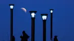 Sejumlah pria berdiri di bawah lampu jalan ketika fenomena gerhana bulan sebagian (parsial) di Buenos Aires, Argentina, Selasa (16/7/2019). Gerhana bulan parsial ini bisa diamati dari Amerika Selatan, Eropa, Afrika, Asia dan Australia. (AP Photo/Natacha Pisarenko)