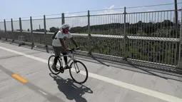 Pengendara sepeda melintasi jembatan di dekat sebuah taman pemakaman di New York, Amerika Serikat (AS) (29/7/2020). Kematian akibat COVID-19 di AS telah menembus angka 150.000 pada Rabu (29/7), tepatnya 150.034 hingga pukul 15.35 waktu setempat atau Kamis (30/7) pukul 02.35 WIB. (Xinhua/Wang Ying)