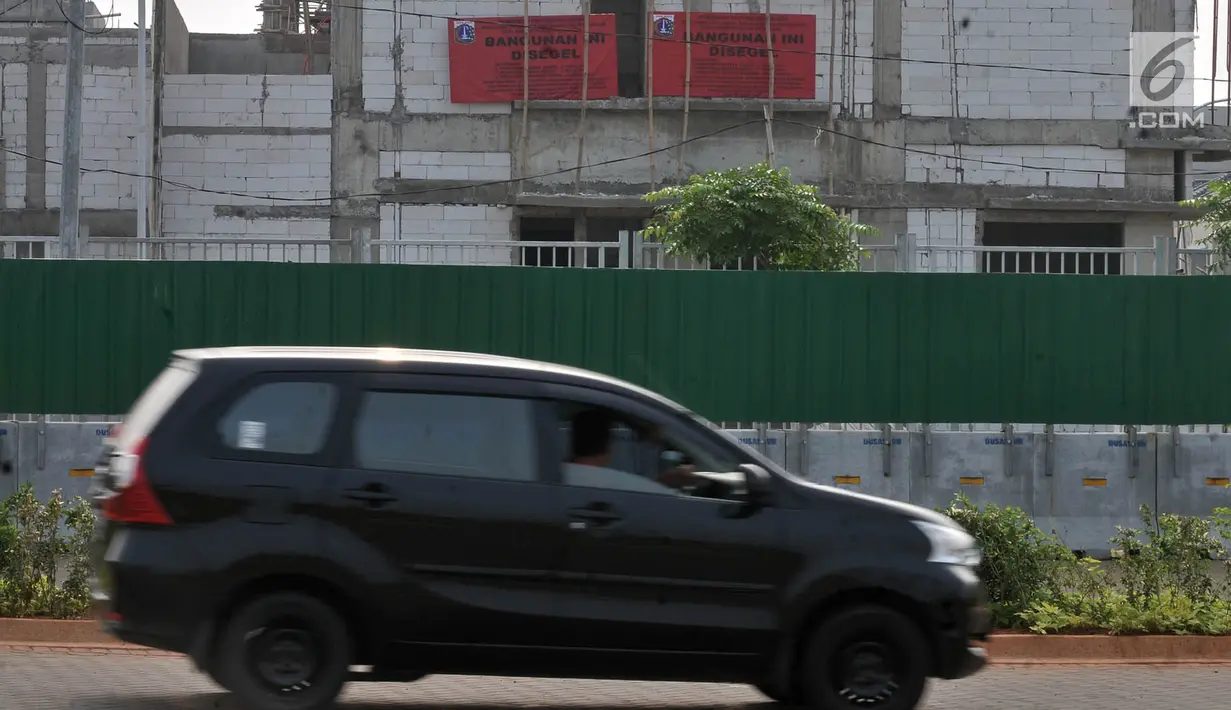 Mobil melintas di depan bangunan proyek reklamasi Pulau D usai penyegelan oleh Pemprov DKI, Kamis (7/6). Bangunan yang disegel terdiri atas 409 rumah, 212 rumah kantor, dan 313 unit rukan serta rumah tinggal yang disatukan. (Liputan6.com/Iqbal Nugroho)