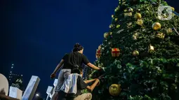 Pekerja menyelesaikan pembuatan Pohon Natal di Thamrin 10, Jakarta, Selasa (22/12/2020). Pemprov DKI mendirikan pohon Natal setinggi 12 meter di Thamrin 10 untuk memeriahkan suasana Natal. (Liputan6.com/Faizal Fanani)