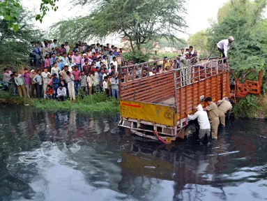 Sebuah truk yang membawa sejumlah orang usai kembali dari upacara pernikahan masuk ke sungai di Etah, India, Jumat (5/5).  Sekitar 14 orang dikabarkan meninggal dalam peristiwa tersebut. (AFP/STR)