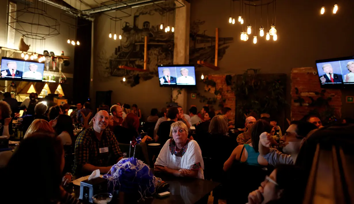 Pendukung Partai Demokrat terlihat serius menyaksikan debat Capres AS Donald Trump dan Hillary Clinton di Sebuah Restoran di Meksiko, (19/10). Debat kali ini menjadi pertarungan terakhir keduanya jelang Pemilu di AS. (Reuters/Carlos Jasso) 