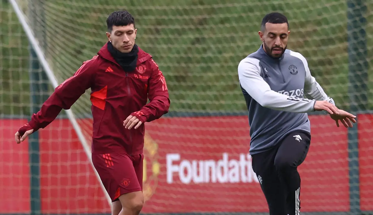 Bek MU, Lisandro Martinez (kiri), melakukan gerakan ringan didampingi asisten pelatih saat sesi latihan yang berlangsung di Carrington, Manchester, Selasa (12/12/2023) dini hari WIB. (AFP/Darren Staples)