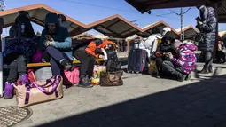 Pengungsi terlihat saat mereka menunggu transportasi lebih lanjut di stasiun kereta api di Przemysl, Polandia pada 17 Maret 2022. Lebih dari tiga juta warga Ukraina telah melarikan diri melintasi perbatasan, kebanyakan perempuan dan anak-anak, menurut PBB. (Wojtek RADWANSKI/AFP)