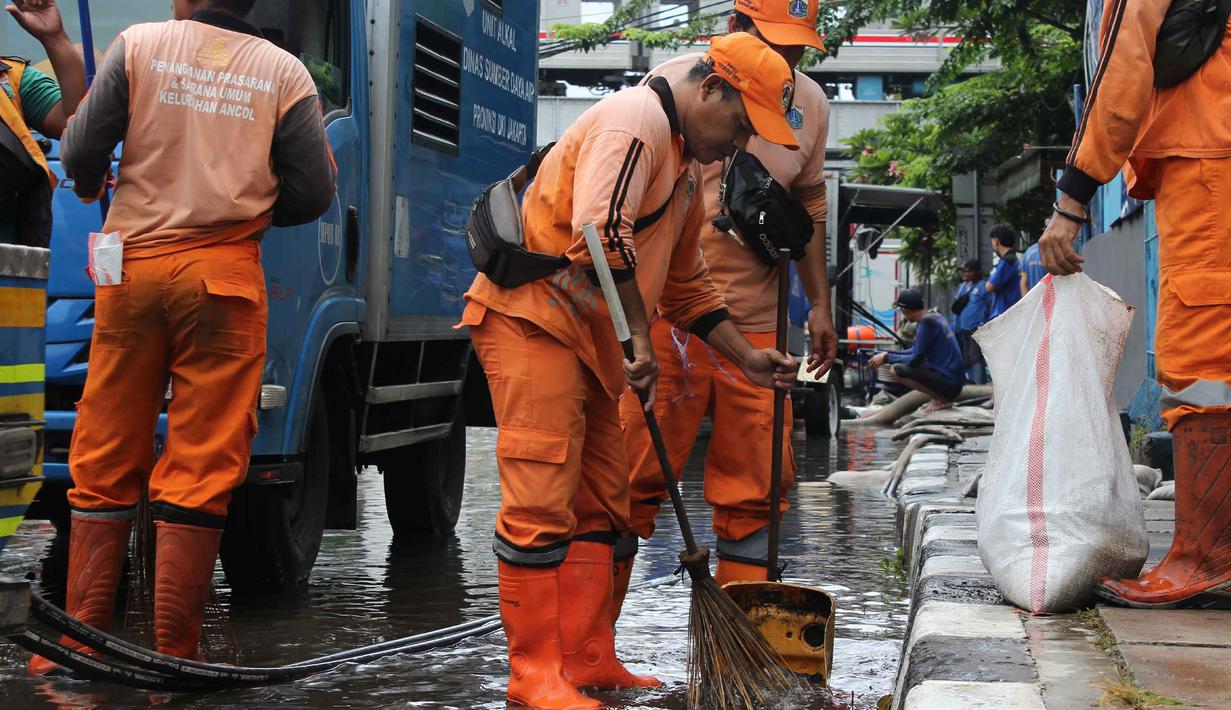 Tidak hanya petugas dari Dinas Sumber Daya Air (SDA) DKI Jakarta, beberapa personel dari Penanganan Prasarana dan Sarana Umum (PPSU) turut dikerahkan untuk menyapu dan membersihkan sisa lumpur yang mengendap di badan jalan. Tampak dalam foto, petugas Penanganan Prasarana dan Sarana Umum (PPSU) DKI Jakarta membersihkan sisa lumpur di Jalan Gunung Sahari Raya atau tepat di depan Mangga Dua Square, Jakarta, Selasa (13/1/2026). (merdeka.com/magang/Rendi Saputra)