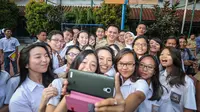Gubernur DKI Jakarta Basuki Tjahaja Purnama (Ahok) berfoto selfie bersama para siswa SMA Negeri 2 Jakarta saat meninjau pelaksanaan Ujian Nasional (UN) di sekolah tersebut, Selasa (14/4/2015). (Liputan6.com/Faizal Fanani)
