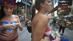 Dua orang wanita sambil memegang duit hasil foto telanjang dada mengelilingi kawasan Times Square, New York,AS, Selasa (18/8/2015).  Para wanita ini biasa disebut dengan desnudas. (REUTERS/Carlo Allegri)
