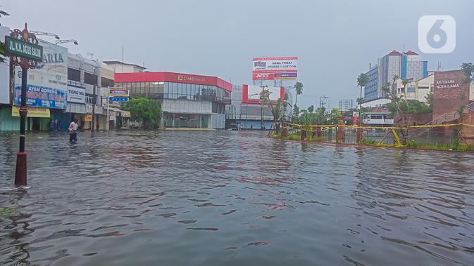 Seorang pria menerobos banjir yang mengepung Kota Semarang, Jawa Tengah, Sabtu (6/2/2021). Hujan deras sejak Jumat malam hingga Sabtu pagi, 6 Februari 2021 membuat sejumlah kawasan di Kota Semarang dikepung banjir. (Liputan6.com/Gholib)