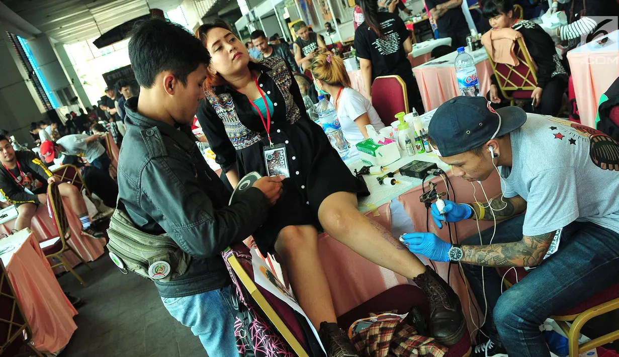 Seorang wanita saat ditato dibagian kakinya saat mengikuti Event tato di salah satu Mal di Jakarta, Sabtu (23/9). Event tato terbesar Se-Jakarta ini sudah ke empat kalinya di adakan. (Liputan6.com/Helmi Afandi)