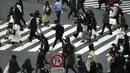 Orang-orang yang mengenakan masker berjalan di sepanjang penyeberangan pejalan kaki di daerah Shibuya, Tokyo, Selasa (5/1/2021). Pemerintah Jepang sedang mempertimbangkan mendeklarasikan keadaan darurat untuk Tokyo karena kasus infeksi virus corona yang terus meningkat. (AP Photo/Eugene Hoshiko)