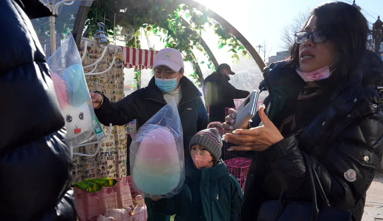 Pelanggan membeli benang gula di toko popup, Beijing, China, 27 Desember 2022. Perusahaan menyambut baik keputusan China untuk mengakhiri karantina bagi pelancong dari luar negeri sebagai langkah penting untuk menghidupkan kembali aktivitas bisnis yang merosot, sementara Jepang mengumumkan pembatasan pengunjung saat infeksi melonjak. (AP Photo/Ng Han Guan)