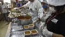 Relawan dari asosiasi Nass el-Khir mengemas kotak makanan sebelum didistribusikan kepada mereka yang membutuhkan selama bulan suci Ramadan di Aljir, Aljazair, Senin (18/5/2020). (RYAD KRAMDI/AFP)