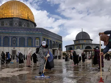 Relawan Palestina membersihkan tanah di luar Masjid Dome of Rock di Kompleks Masjid Al Aqsa, Kota Tua Yerusalem, Sabtu (18/3/2023). (AP Photo/Mahmoud Illean)