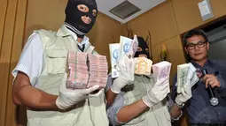 Petugas memperlihatkan barang bukti berupa mata uang dollar AS dan dollar Singapura yang ditemukan dalam operasi tangkap tangan terhadap Gubernur Riau Annas Maamun, Jakarta, (26/9/14). (Liputan6.com/Miftahul Hayat) 