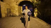 Nizar al-Dabbas Palestina berusia lima puluh tahun, seorang "Musaharati" yang memainkan peran tradisional sebagai "penabuh drum Ramadhan", membangunkan umat Islam untuk makan sahur sebelum fajar selama bulan suci Ramadhan di Khan Yunis di Jalur Gaza selatan (5/4/2022). (AFP/Said Khatib)
