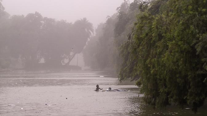 Anak-anak berenang di kolam saat badai debu menerjang New Delhi, India, Rabu (2/5). Badai terjadi di Negara Bagian Uttar Pradesh dan Rajasthan. (CHANDAN KHANNA/AFP)