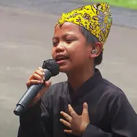 Farel Prayoga bernyanyi di hadapan Presiden Jokowi beserta para menteri dengan mengenakan beskap berwarna hitam dan celana panjang. (Tangkapan layar YouTube Sekretariat Presiden)