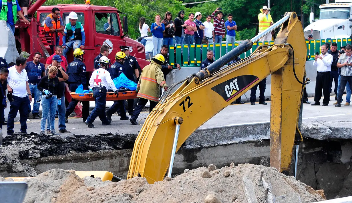 Regu penyelamat mengevakuasi mayat dari lokasi lubang yang menelan sebuah mobil di jalan raya Meksiko-Cuenava, Meksiko, Rabu (12/7). Lubang itu muncul akibat erosi sistem pengeringan yang membentang sekira 15 meter di bawah jalan. (AP/Tony Rivera)