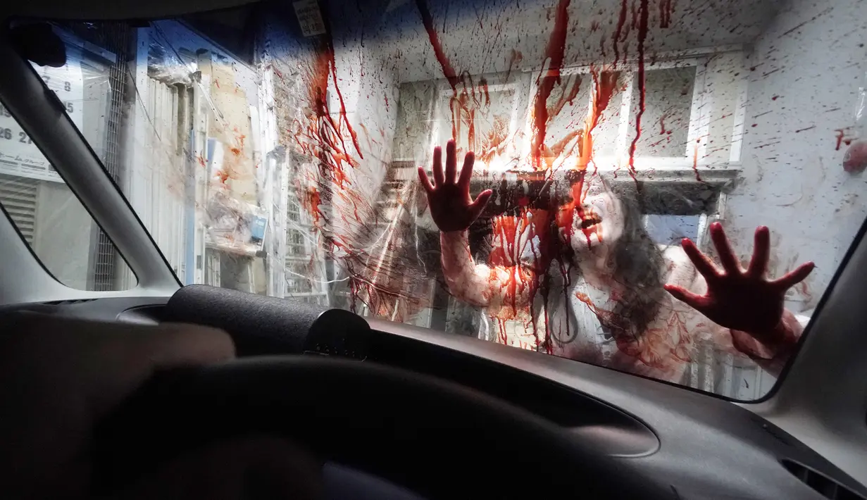 Pemeran zombie tampil dengan darah palsu yang disiramkan ke kaca kendaraan saat demonstrasi pertunjukan rumah hantu drive-in di Tokyo, Jepang, Selasa (18/8/2020). Rumah hantu drive-in ini diadakan di tengah pandemi COVID-19. (AP Photo/Eugene Hoshiko)