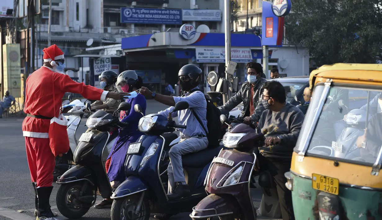 Aksi presiden Angel Foundation dan pekerja sosial, Rufas Christian, yang berpakaian Sinterklas memberikan masker kepada pengendara di persimpangan lalu lintas di Ahmedabad, India, Kamis (17/12/2020). Aksi itu sebagai bagian dari kampanye kesadaran melawan penyebaran COVID-19. (SAM PANTHAKY/AFP)