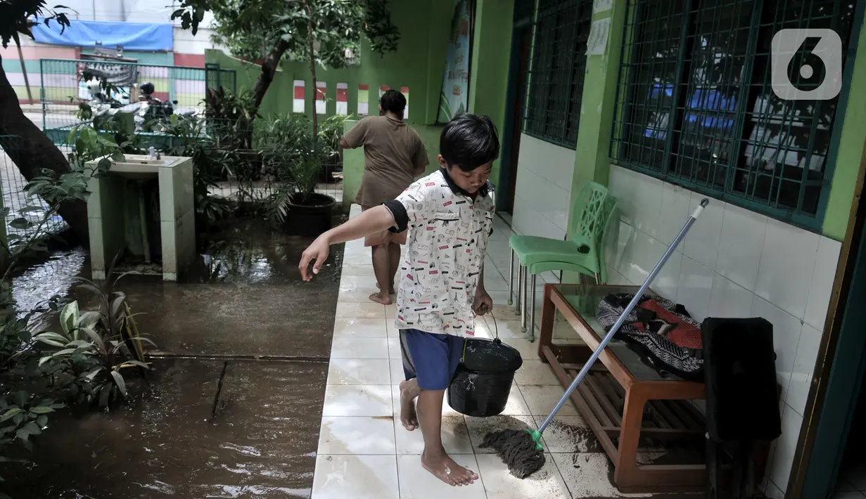 Seorang murid membersihkan ruangan akibat banjir di Madrasah Tsanawiyah (MTs) Nur Attaqwa, Pegangsaan Dua, Kelapa Gading, Jakarta Utara, Senin (24/2/2020). Banjir yang terjadi sejak Minggu (23/2) kemarin mengakibatkan kegiatan belajar di MTs itu terpaksa diliburkan. (merdeka.com/Iqbal S Nugroho)