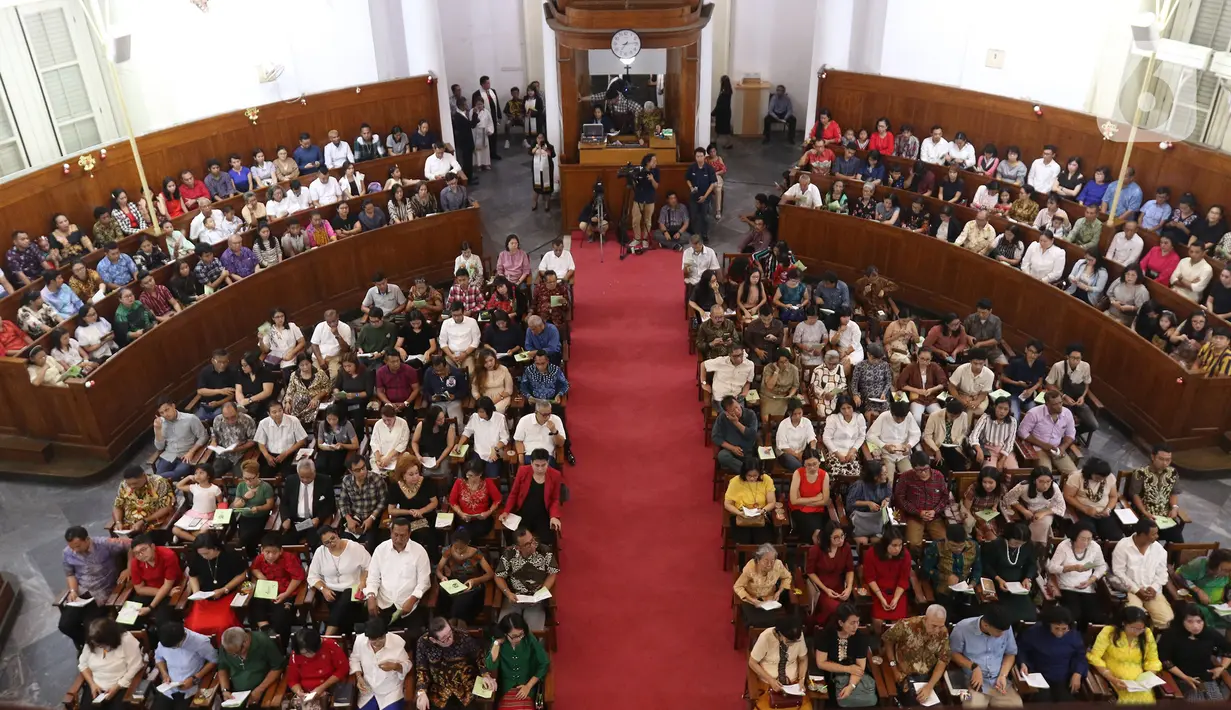 Jemaat menyalakan lilin saat mengikuti kebaktian malam Natal 2019 di Gereja Protestan Indonesia Bagian Barat (GPIB) Imanuel,  Jakarta, Selasa (24/12/2019). (Liputan6.com/Herman Zakharia)