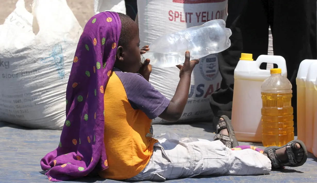 Seorang anak minum air di dekat jatah bantuan makanan dari World Food Programme di Chiredzi Mupinga, Zimbabwe, Selasa (6/10). Puluhan juta orang di sub-Sahara Afrika terancam kelaparan akibat siklus El Nino mencapai puncaknya.(REUTERS/Philimon Bulawayo)