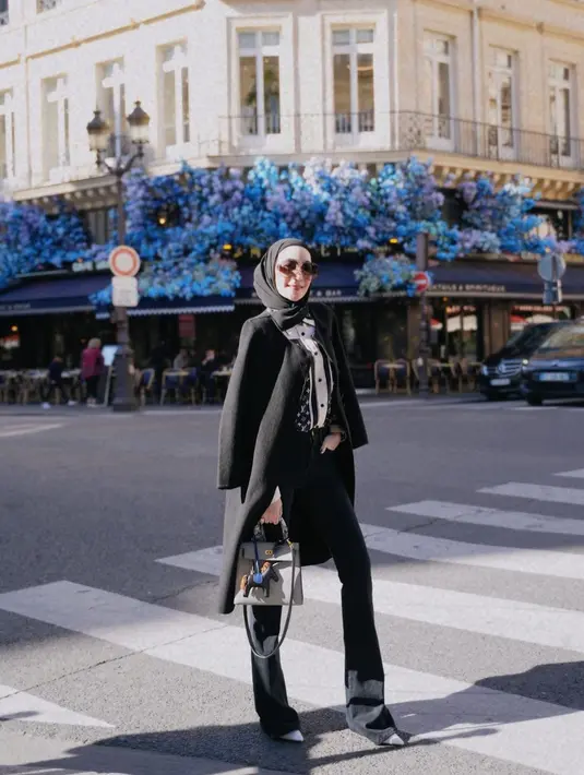 <p>Outfit liburan ala Erin dengan all black outfit. Berpose di jalanan luar negeri, Erin terlihat mengenakan blouse bermotif yang bernuansa hitam-putih, ditumpuknya dengan long coat hitam, dipadu dengan celana panjang dan hijab hitam. Foto: Instagram.</p>