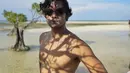 Menikmati pemandangan di pantai, Dwi Sasono memilih bergaya topless dengan kacamata hitam. Tubuh atletisnya membuat ia terlihat makin macho. (Liputan6.com/IG/@dwisasono)