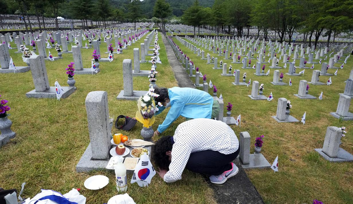 Warga Korea Selatan Lee Myung-ja dan Lee Young-sook (bawah) membungkuk di depan nisan saudara mereka Lee Sun-woo yang gugur saat Perang Korea pada peringatan Hari Pahlawan di Pemakaman Nasional Seoul, Seoul, Korea Selatan, Senin (6/6/2022). (AP Photo /Ahn Young-joon)