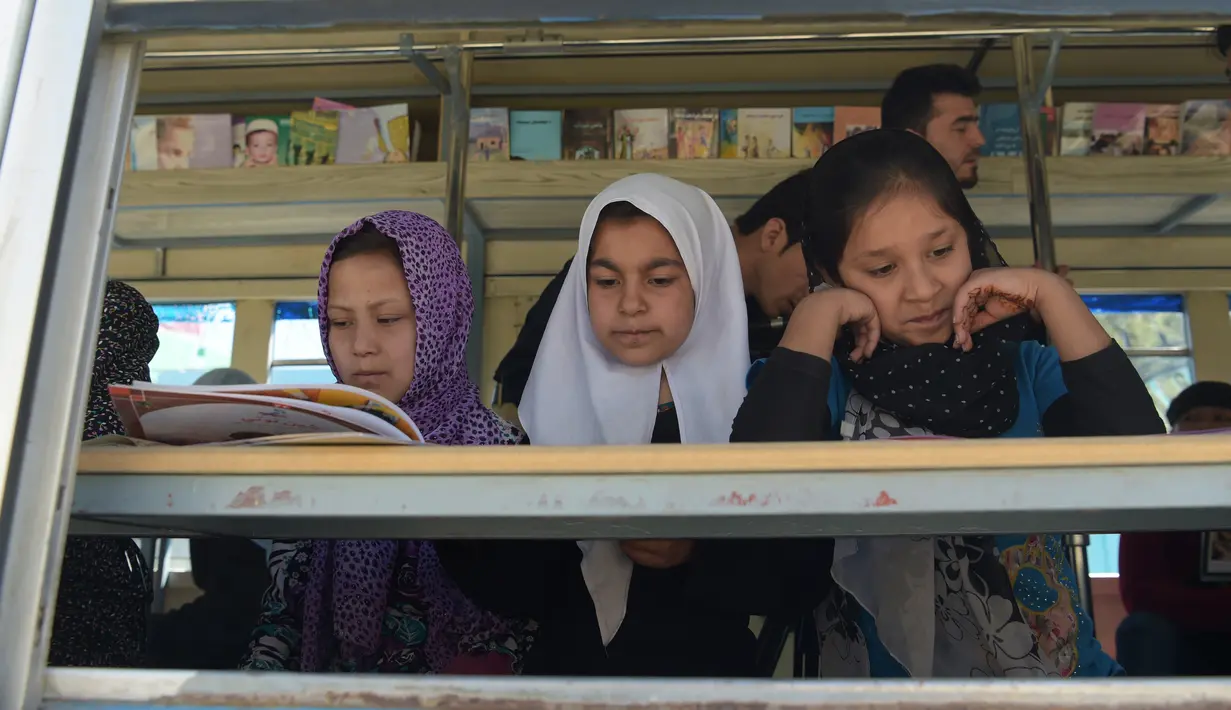 Anak-anak Afghanistan membaca buku dalam bus yang dijadikan perpustakaan keliling di Kabul, 4 April 2018. Perpustakaan keliling adalah inisiatif lulusan Oxford University, Inggris, Freshta Karim yang juga seorang pengungsi Afghanistan. (AFP/Shah MARAI)