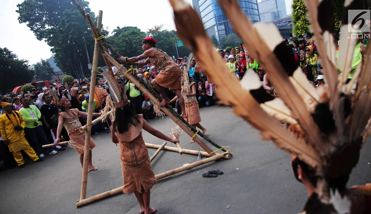 Penari berpakaian adat Dayak melakukan pertunjukan memanjat pohon manau berduri pada pawai budaya saat Car Free Day di kawasan Sudirman, Jakarta, Minggu (29/10). Kegiatan ini dikemas dengan nama Gelar Pesona Budaya Tabalong. (Liputan6.com/Faizal Fanani)