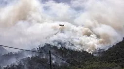Sebuah helikopter militer menjatuhkan air di atas hutan dekat Desa Schinos, Korintus, Yunani, Kamis (20/5/2021). Kebakaran hutan besar di sebelah barat Athena merusak rumah-rumah dan mendorong evakuasi.  (AP Photo/Petros Giannakouris)