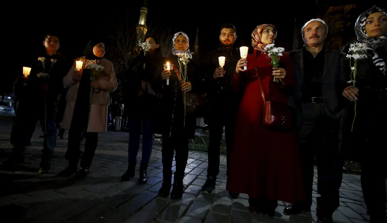 Warga Suriah yang tinggal di Turki memegang lilin dan bunga di lokasi bom bunuh diri di Sultanahmet Square, Istanbul, Rabu (13/1). Bunga dan lilin tersebut wujud belasungkawa untuk korban ledakan di Turki. (REUTERS/Osman Orsal)
