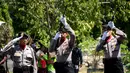Petugas melepas tembakan salvo ke udara saat upacara pemakaman Aipda Wayan Sudarsa, polisi korban pembunuhan pasangan bule, Bali, Minggu (21/8). Prosesi secara institusi Polri itu dilakukan sebelum jenazah dibakar sesuai adat Hindu. (SONNY Tumbelaka/AFP)