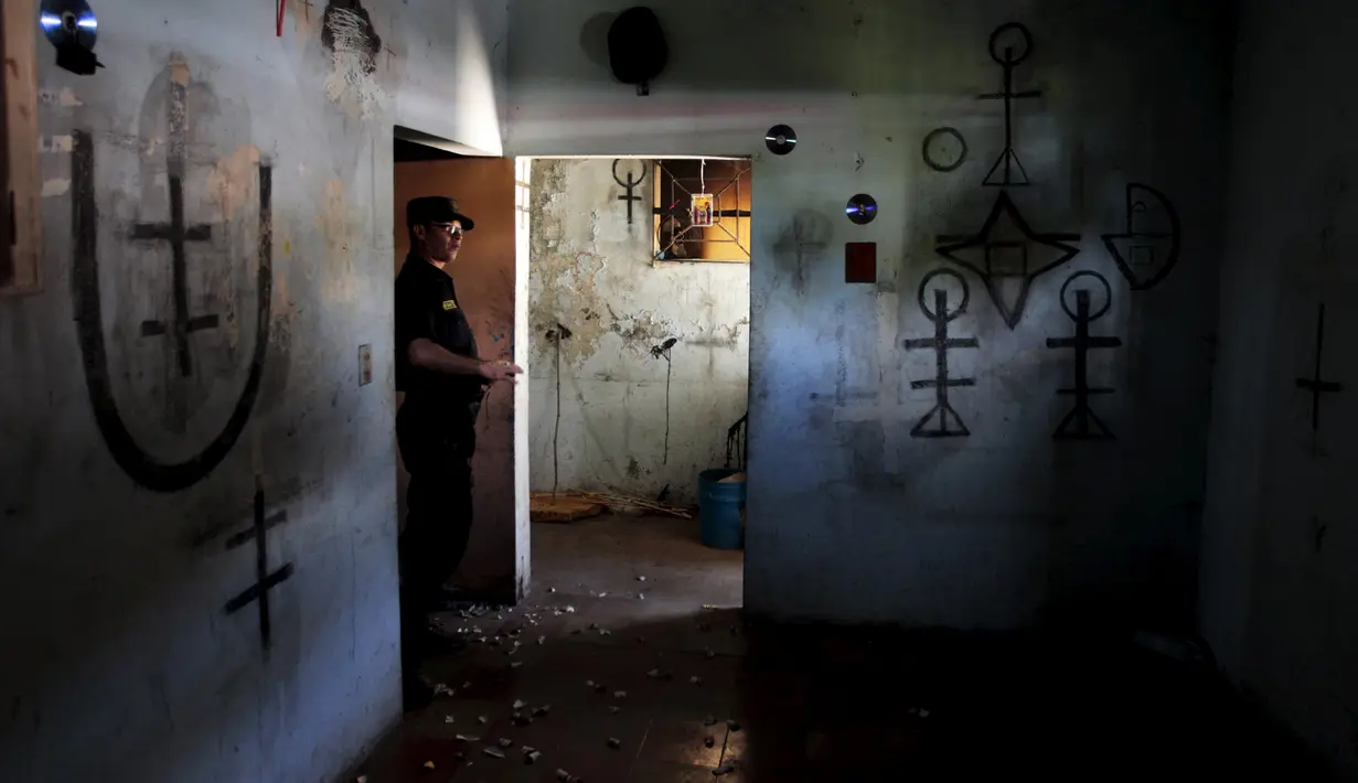 Polisi memasuki rumah dengan simbol - simbol yang dibuat geng Mara Salvatrucha di Mejicanos, El Salvador, (9/12). Kepolisian El Salvador juga akan menghapus semua gambar atau simbol yang dibuat oleh geng Mara Salvatrucha. (REUTERS/Jose Cabezas)