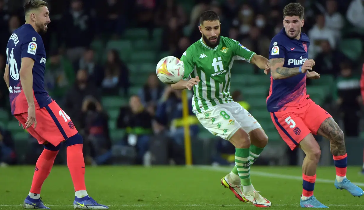Gelandang Real Betis Nabil Fekir (tengah) berebut bola dengan gelandang Atletico Madrid Rodrigo De Paul (kanan) pada laga Pekan Ke-27 La Liga Spanyol di Estadio Benito Villamarin, Sevilla, Senin (7/3/2022) dini hari WIB. Atletico Madrid menang 3-1 atas Real Betis. (CRISTINA QUICLER / AFP)